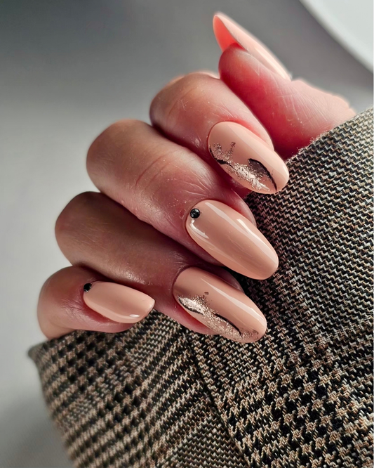 A close-up of a hand with almond-shaped nails styled in a glossy nude pink color, featuring Phenomenail™ M.E.T.A Pro Milly peach nude gel polish bottle